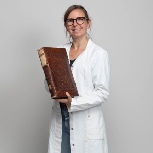 Expert Imke Neels met een oud boek in haar handen