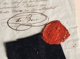 Een zwart lapje stof met een waszegel op een handgeschreven brief