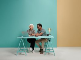 Vrouw en man zitten samen achter een laptop.