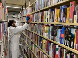 Een KB-medewerker die boeken uit een kast haalt.