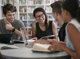 Lachende jongeren met laptops en boeken