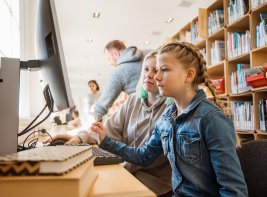 Twee meisjes achter een computer in een bibliotheek.