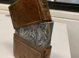 Een boek in een leren cassette, de bovenste helft los op het boek