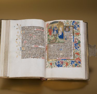 Getijdenboek van de Zwarte-Ogen-meesters opengeklapt bij een miniatuur van de aanbidding van het Christuskind