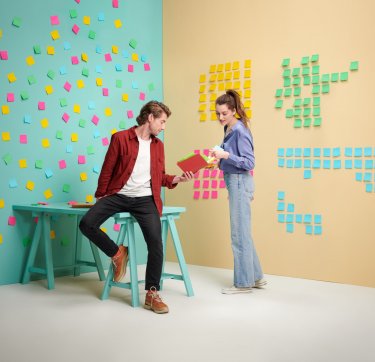 Foto van man en vrouw met post-it notes op de achtergrond. (stagelopen)