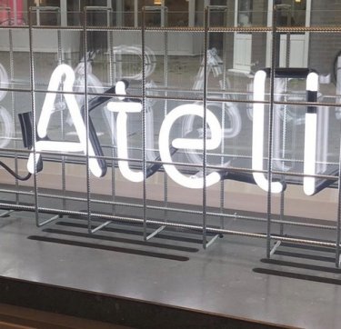 Voor het raam van de KB staan in lichtgevende letters de woorden KB Atelier geschreven.