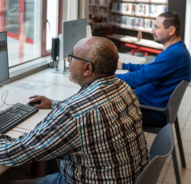 Twee mannen achter computers in een bibliotheek