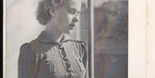 Een zwartwit foto van een vrouw bij het raam met een gebreid truitje aan. Het is het voorbeeld van een breipatroon voor een sportieve damesblouse uit het Haka breiboek (1937). 