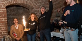 Winnaars HackaLOD juichen, met taart in de hand met vuurwerk erop.