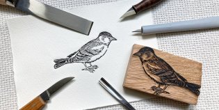 Een houtdruk van een vogel, omringd door houtbewerkgereedschap en het houtblok