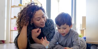 Vrouw en kind liggen op de grond en kijken samen naar een tablet.