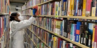 Een KB-medewerker die boeken uit een kast haalt.