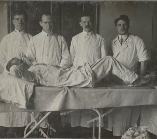 4 artsen in een operatiekamer aan het bed van een patiënt.