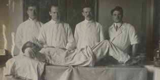 4 artsen in een operatiekamer aan het bed van een patiënt.