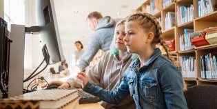 Twee meisjes achter een computer in een bibliotheek.