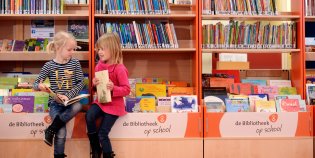 Twee kinderen die op een bak boeken zitten te lezen