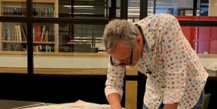 Mark van Leijden staat gebogen over een tafel met een krant.