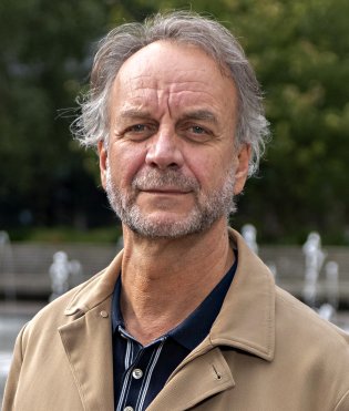 Portretfoto van fotograaf Jos, hij kijkt in de camera en lacht.