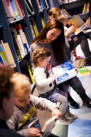 Volwassenen lezen kinderen voor in de bibliotheek
