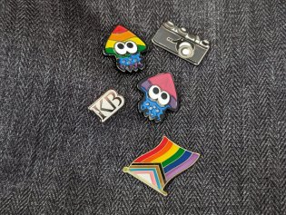 Een rugzak met meerdere Pride pins en een pin met het KB-logo