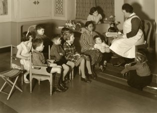Zuster leest voor aan groep kinderen. Programma Indisch Erfgoed Digitaal.