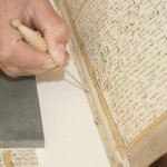 Boekrestauratie: op de afbeelding worden naaigaten voorgeprikt in een oud boek.