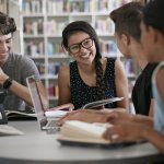 Lachende jongeren met laptops en boeken