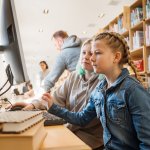 Twee meisjes achter een computer in een bibliotheek.