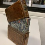 Een boek in een leren cassette, de bovenste helft los op het boek
