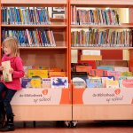 Twee kinderen die op een bak boeken zitten te lezen