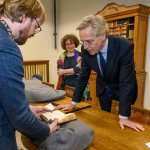 Collectiespecialist Jeroen Vandommele toont minister Dijkgraaf een boek uit de collectie, algemeen directeur Lily Knibbeler kijkt toe.