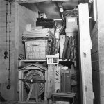 Diverse kunstobjecten tijdens de oorlog opgeslagen in een houten kist in een depot. Met linksonder opgerold, het fameuze schilderij De Nachtwacht van Rembrandt. Dagelijks werd de rol gedraaid om de druk op het kwetsbare schilderwerk te verdelen. Foto: Nationaal Archief.