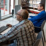 Twee mannen achter computers in een bibliotheek