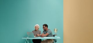 Vrouw en man zitten samen achter een laptop.