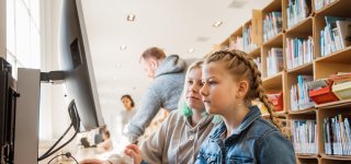 Twee meisjes achter een computer in een bibliotheek.