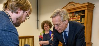 Collectiespecialist Jeroen Vandommele toont minister Dijkgraaf een boek uit de collectie, algemeen directeur Lily Knibbeler kijkt toe.