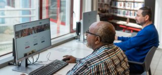 Twee mannen achter computers in een bibliotheek
