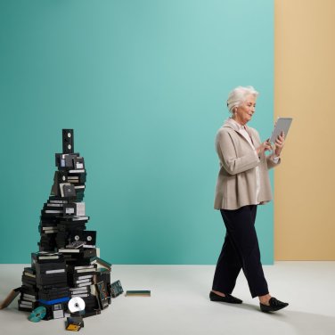 Vrouw loopt met een tablet in de hand weg van een stapel boeken